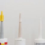 Ensemble de divers tubes en plastique avec colle pour travaux de rénovation en atelier sur fond blanc
