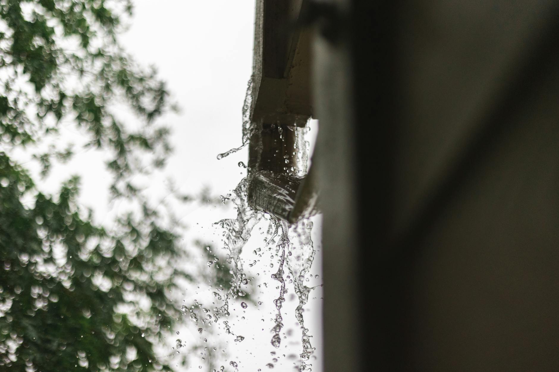 Gros plan de l'eau de pluie s'écoulant d'une gouttière, capturée lors d'une pluie à Houston.