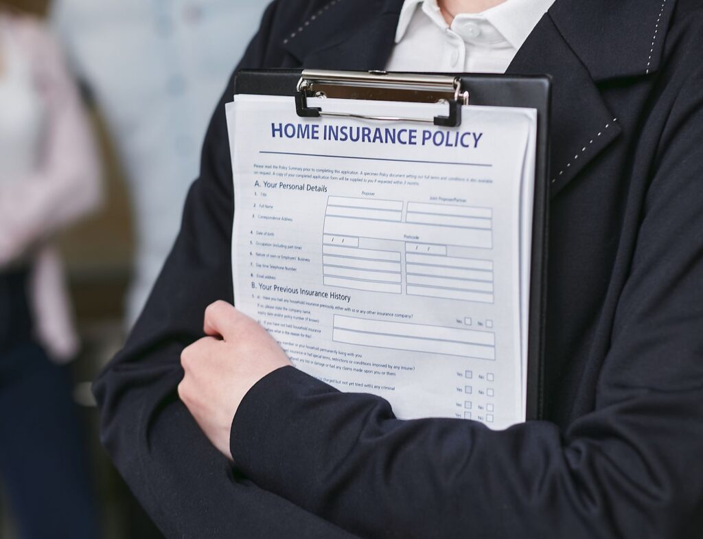 Gros plan d'une personne détenant une police d'assurance habitation sur un presse-papiers, capturé à l'intérieur.
