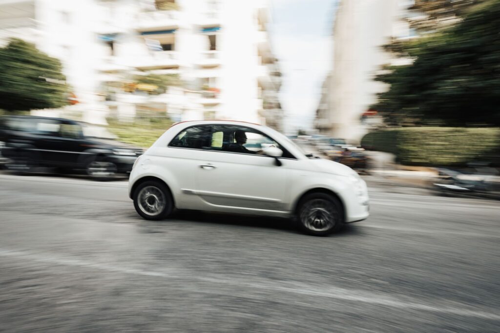 Capture dynamique d'une voiture blanche compacte roulant à toute vitesse dans une rue de la ville avec effet de flou de mouvement.