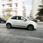 Capture dynamique d'une voiture blanche compacte roulant à toute vitesse dans une rue de la ville avec effet de flou de mouvement.